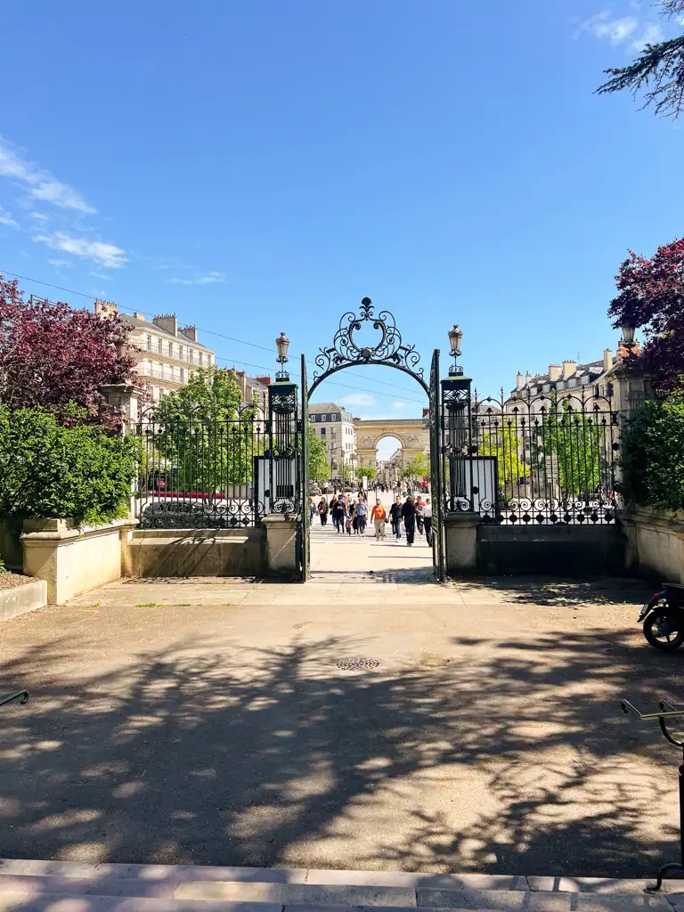 The iron gate entrance to a park on a sunny day. 
