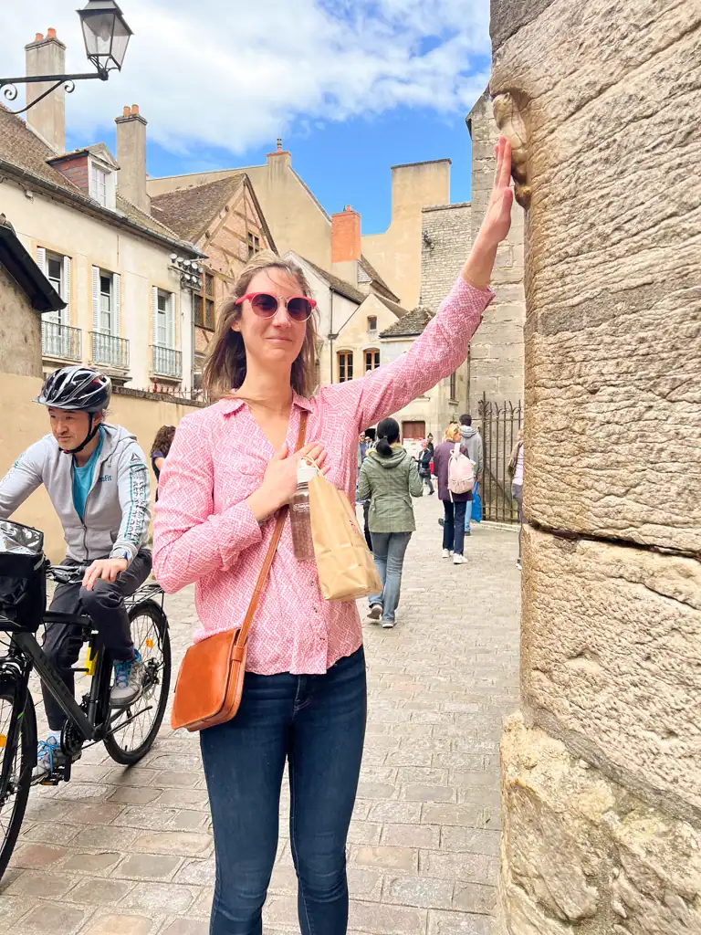 A woman touches the own statue on the side of a French church. 
