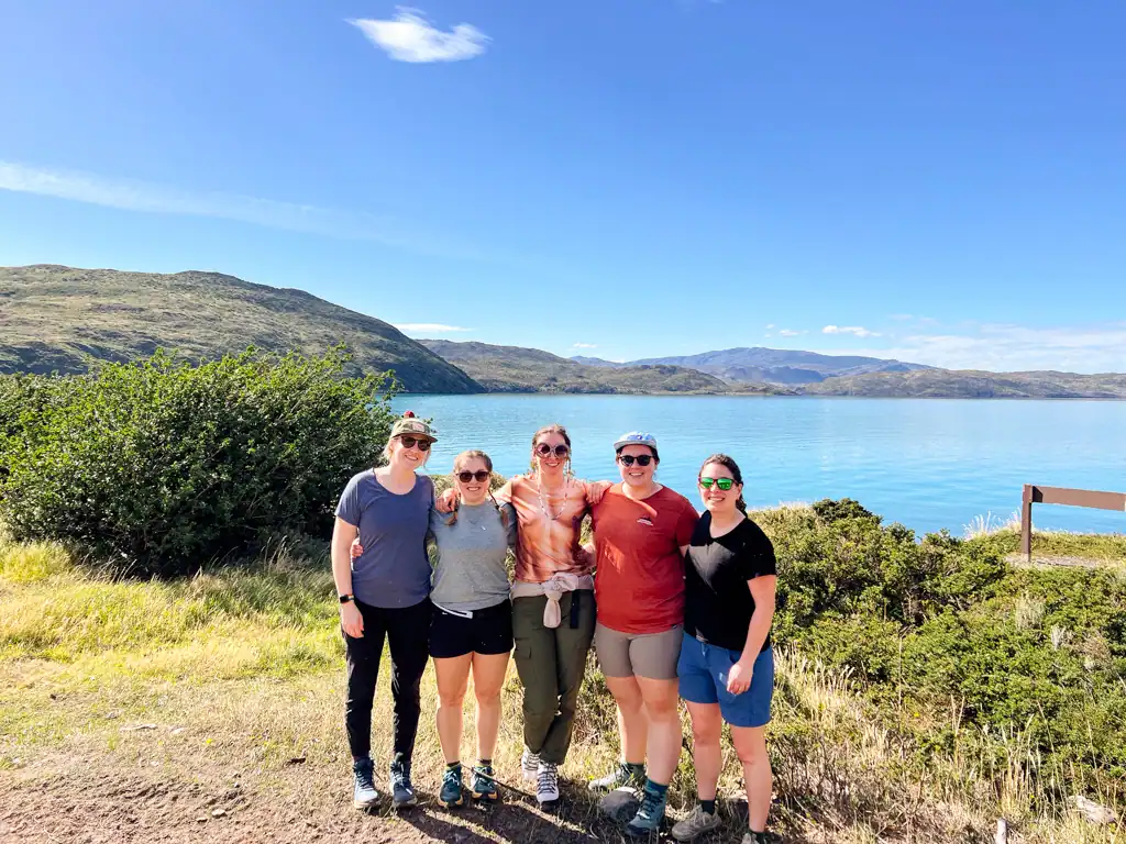 A group of 5 girls stand in front of Lake Pehoe in Patagonia on teh W -trek. 