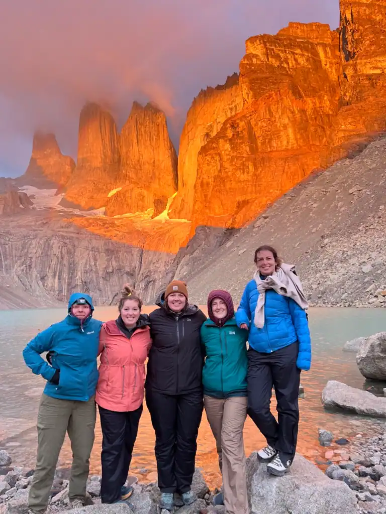 sunrise at the famous towers in patagonia and 5 girls standing in front of the lake. 