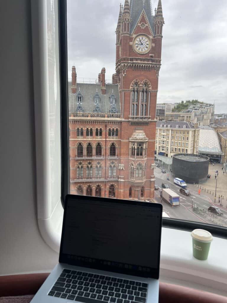 A laptop and coffee with st. pancras in the background in a hotel room the best place to stay in london.