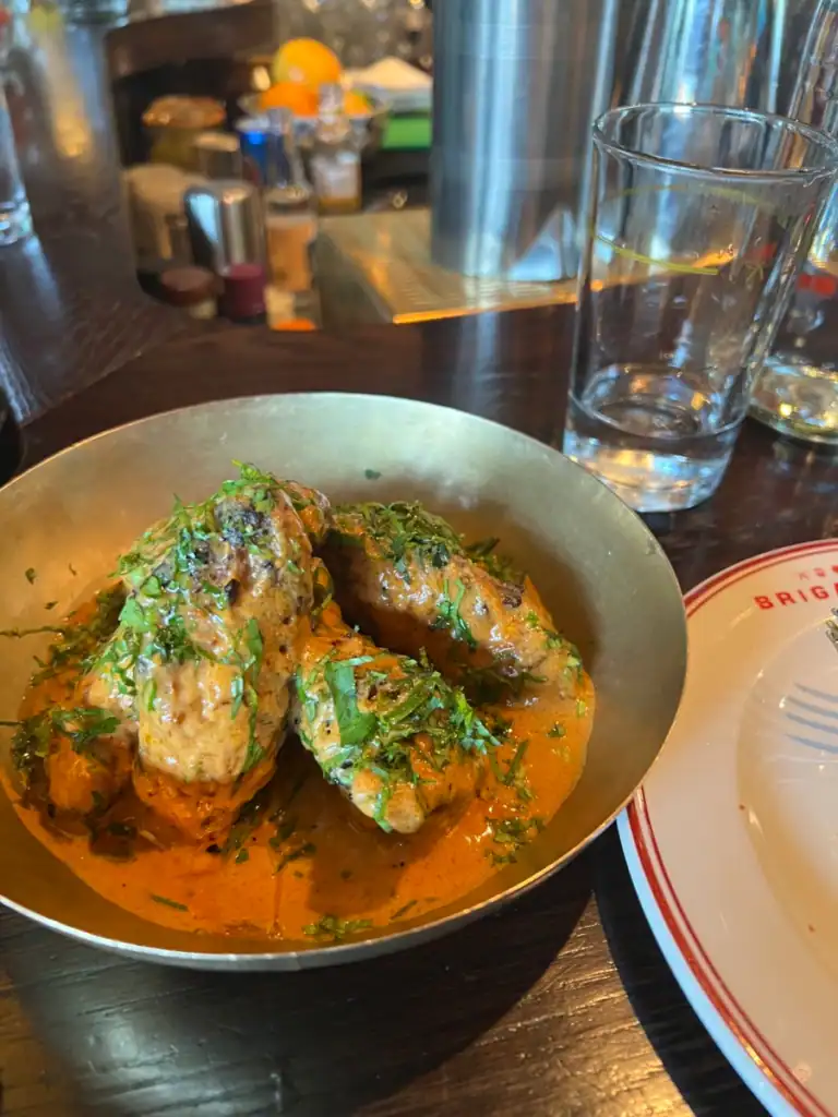 A close up of Brigadiers wings in a gold tin bowl. 