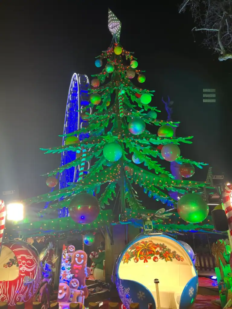 A lit up large christmas tree with ornament rides below. found in the best festivals around the world. 