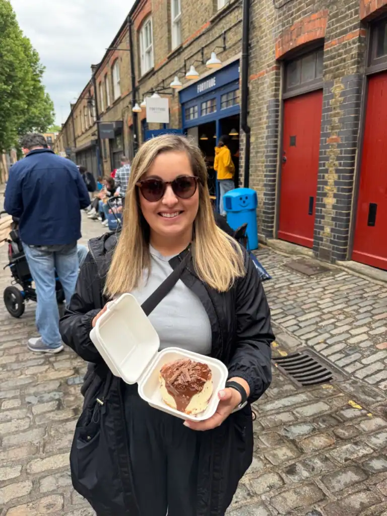 Girl wearing black holds a viral beignet from Fortitude bakehouse on a perfect solo day in london.