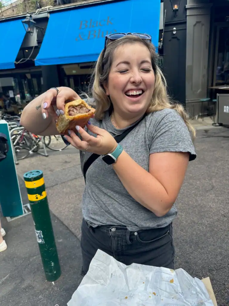 A girl holds up the Ginger pig sausage roll at Borough market. 