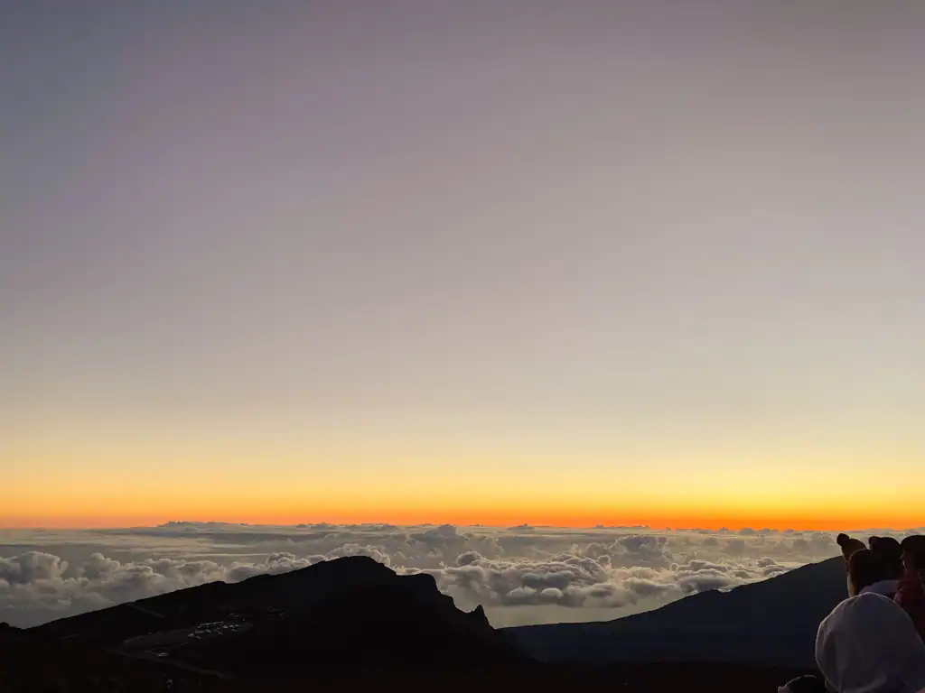 The sun just starting to come up with clouds hanging over the island at Haleakala National Park. 
