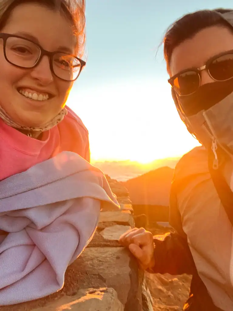 girl and boy are bundled up with a sunrise. 