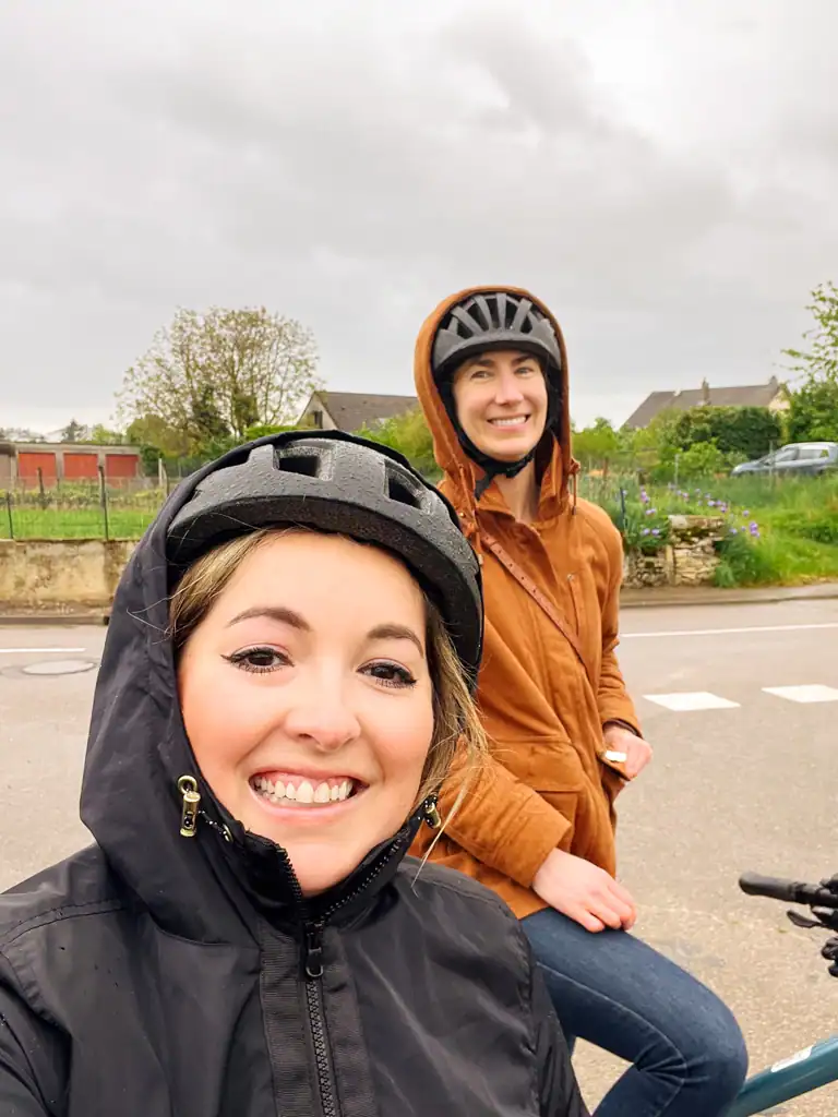 two women posting with their helmets and hoods on their heads on a burgundy wine tour. 