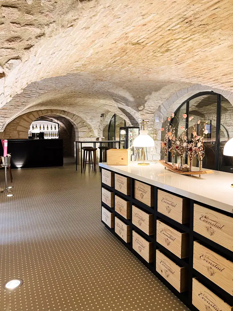A white brick wine cave with a large island filled with the chateau's wine boxes. 