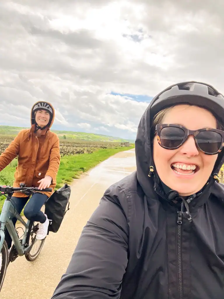 Two girls with helmets and coat hoods on biking on the burgundy wine tour. 