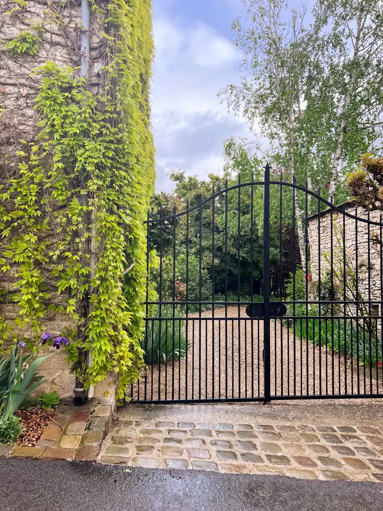 A black metal gate leading to a gravel path in Burgundy wine guide. 