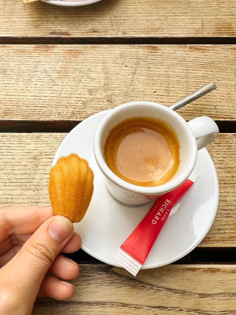 A small espresso with a tiny madeleine cookie. 