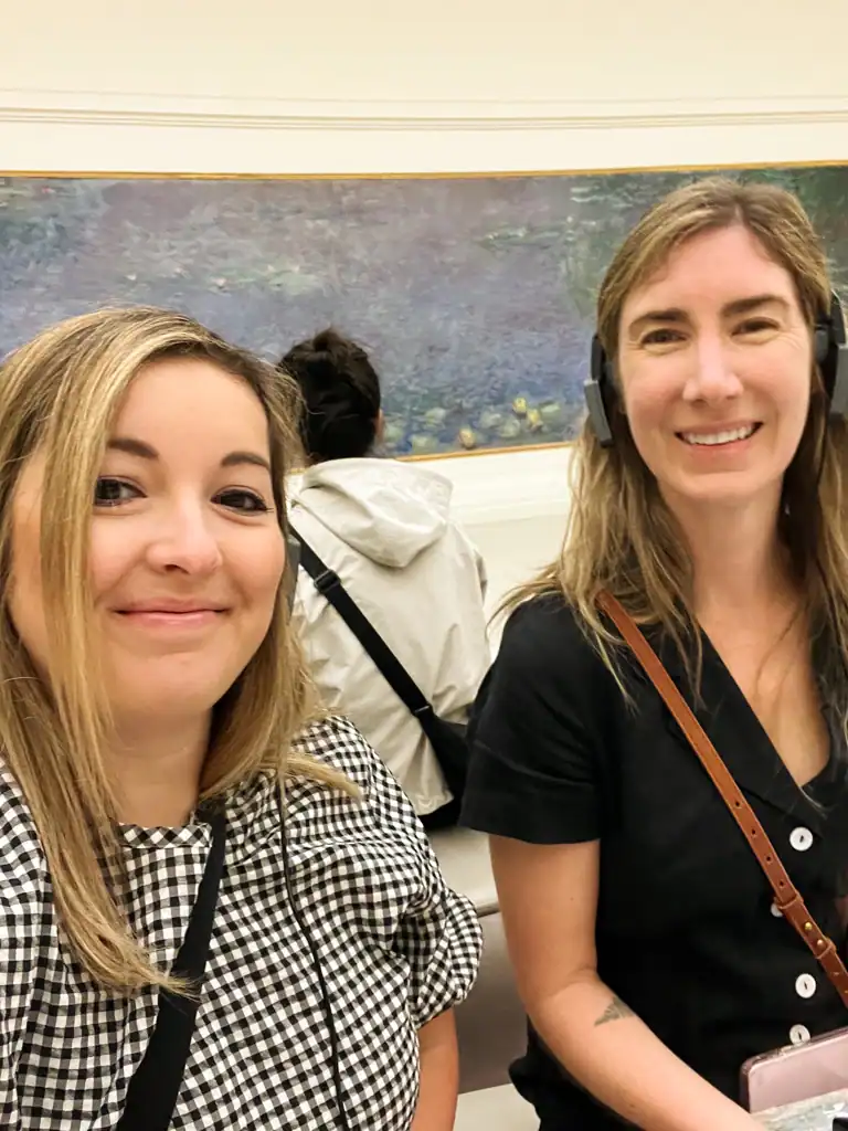 2 girls at the museum with headphones on and monet's water lilies in the background. 