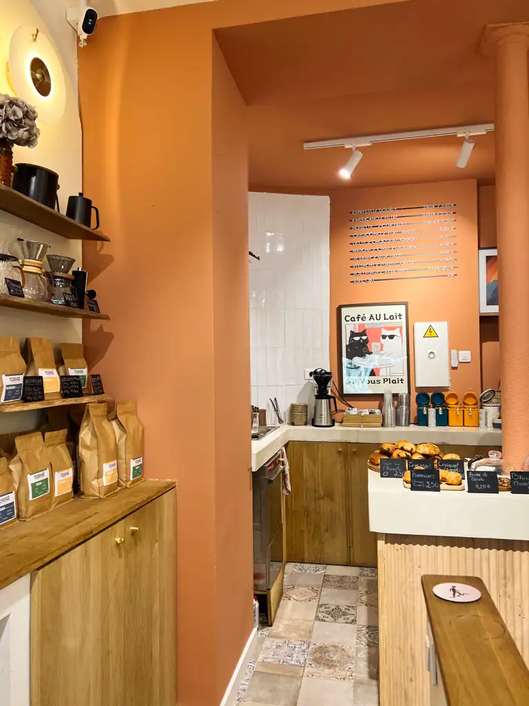 The inside of coffee shop with orange walls, croissants and a cat painting. 