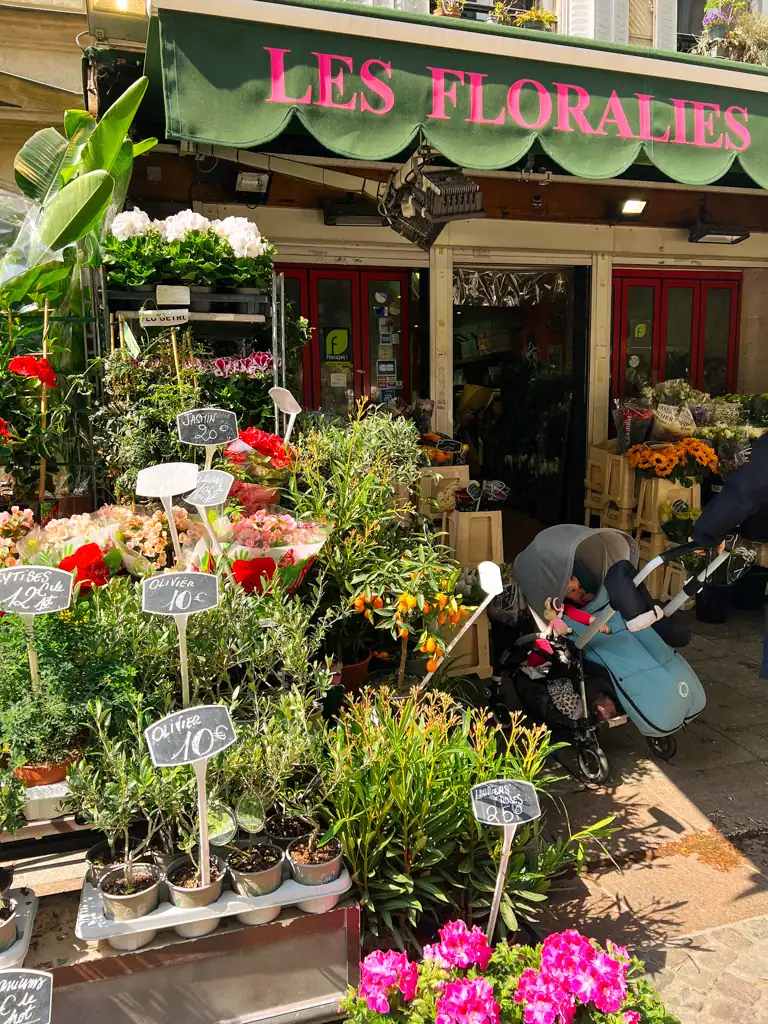 A flower shop with a baby stroller out front on Rue Cler in Paris. 