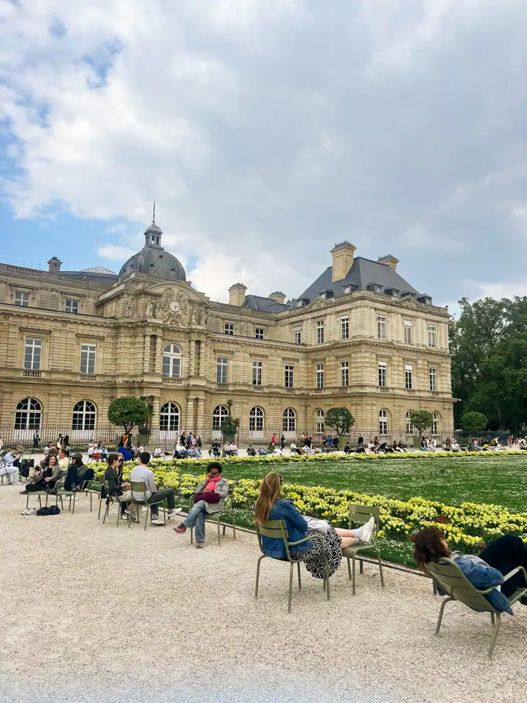 the people sitting near the building in the Luxembourg Park in Paris. 