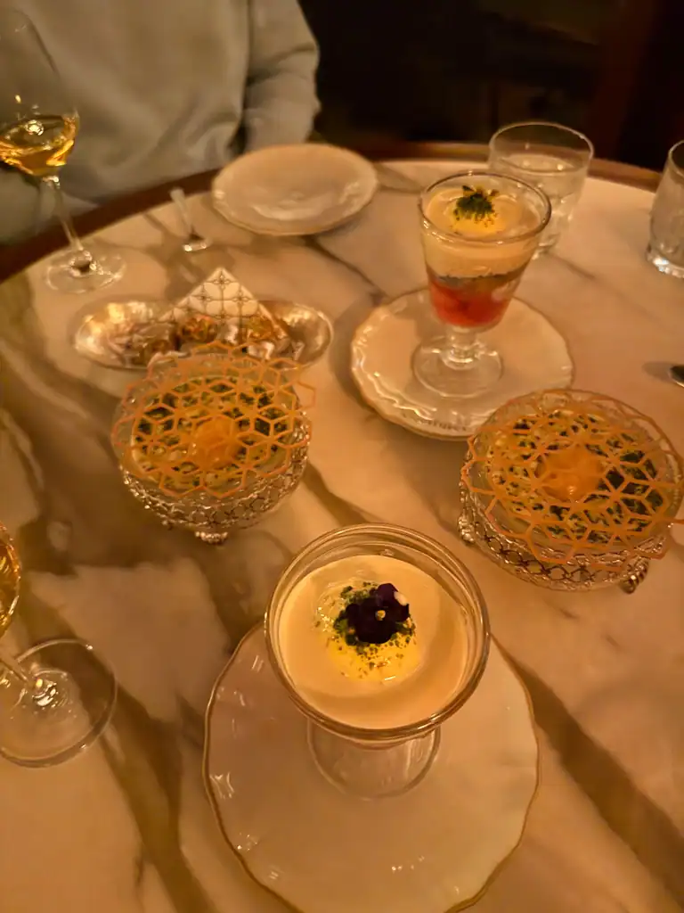 4 desserts on a marble table with various glasses around.
