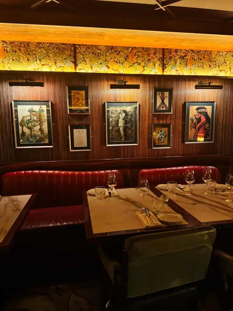 A picture of a wooden wall and red leather booths and marble tables at Gymkhana in London.