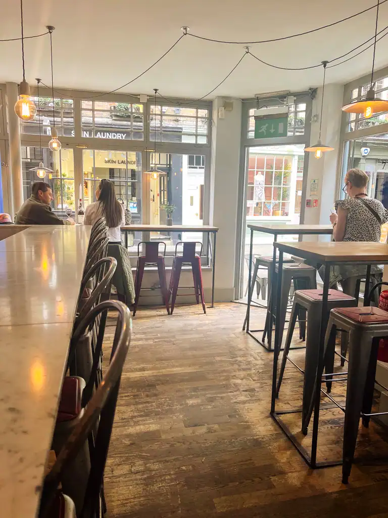 Antidote wine bar with old wood floors, tables and stools on a perfect solo day in london.