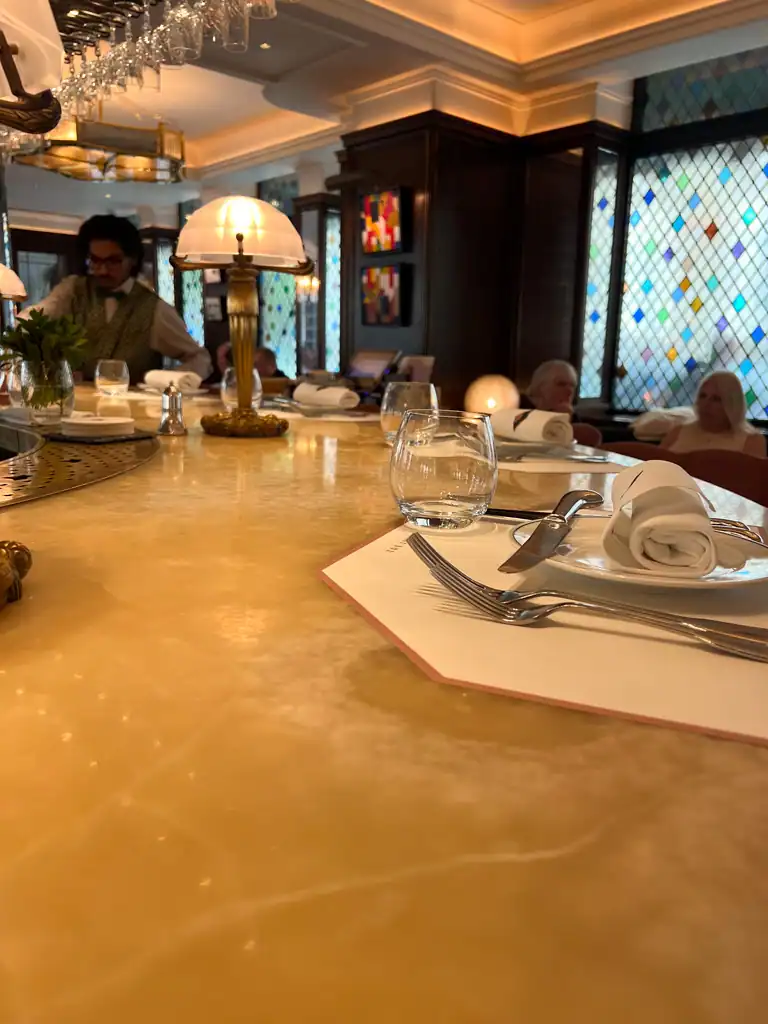 A marble bar with an eclectic lamp and stain glass windows at the Ivey in London. 