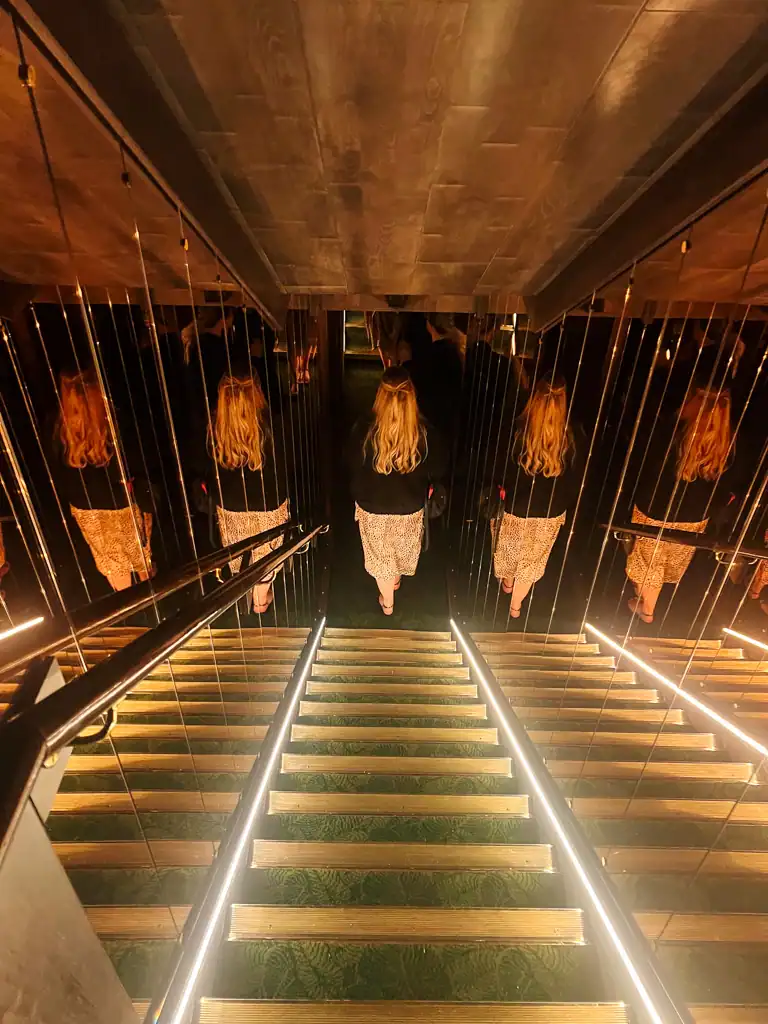 A mirrored walkway with stairs at Gymkhana in London.