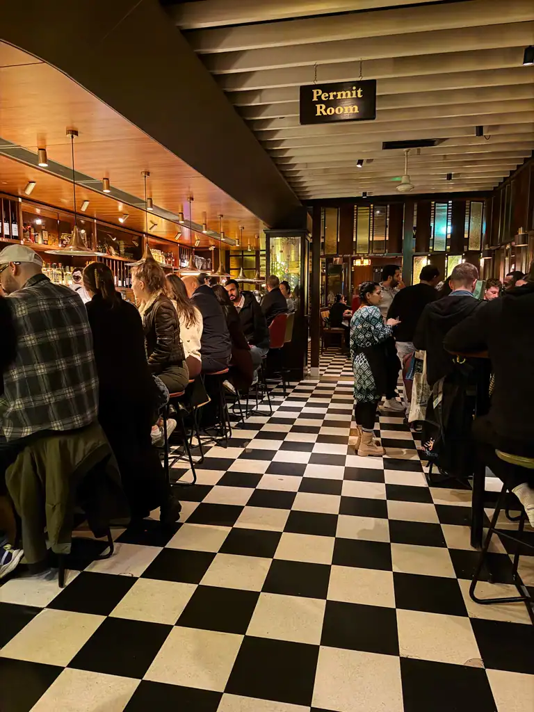 A classic checkered floor in a busy b ar at Dishoom in London.