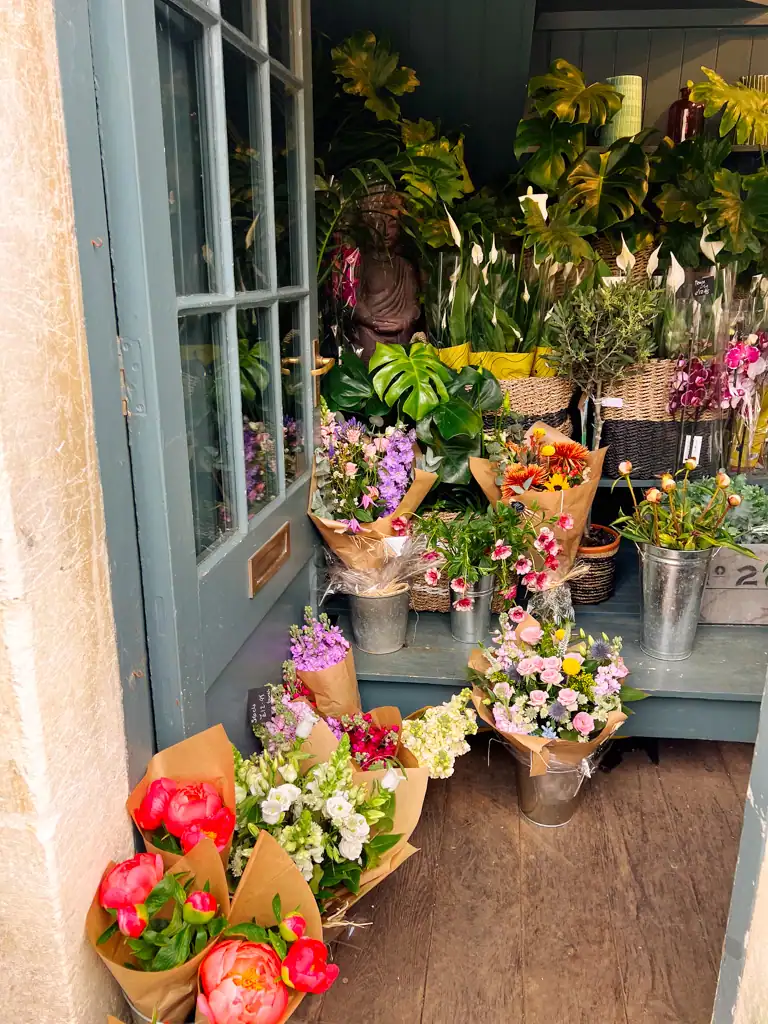 A doorway opened to multiple boquets of flowers and plants set on tiered shelves.