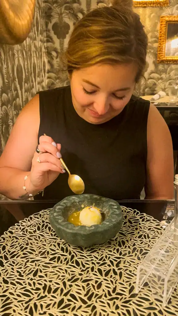 A girl eats a smalls scoop of soret with yellow liquid. 
