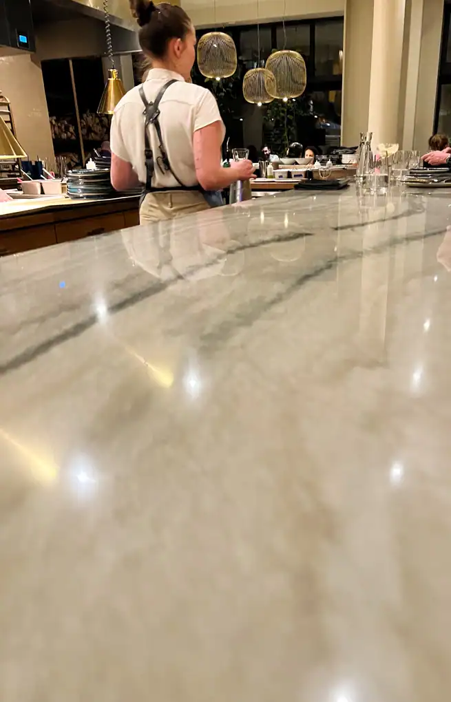 the large marble bar at Kann with a waiter in the apron walking away .