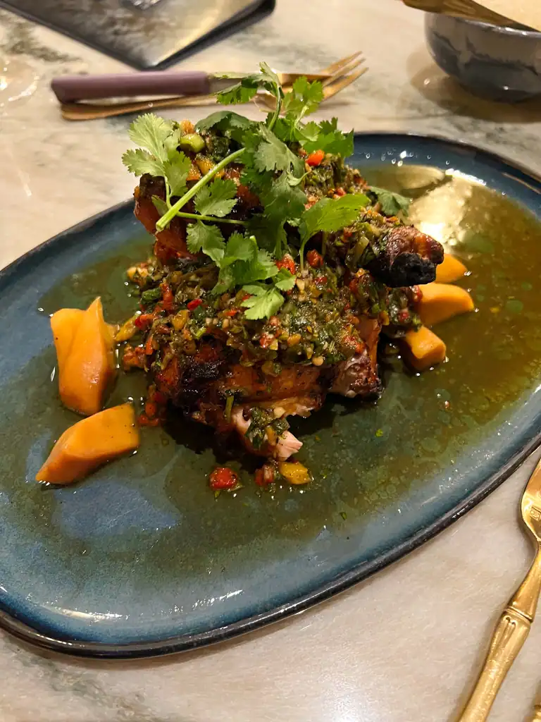 The chicken dish at Kann with fermented mango and a green garnish. 