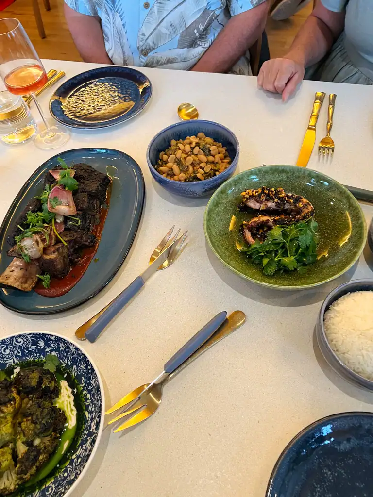 a table with multiple dishes in blue plates on a white table at Kann. 