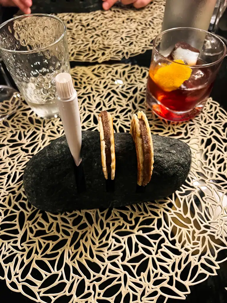 Two tiny oxtail sandwiches held in a rock with toothpaste style sauce. 