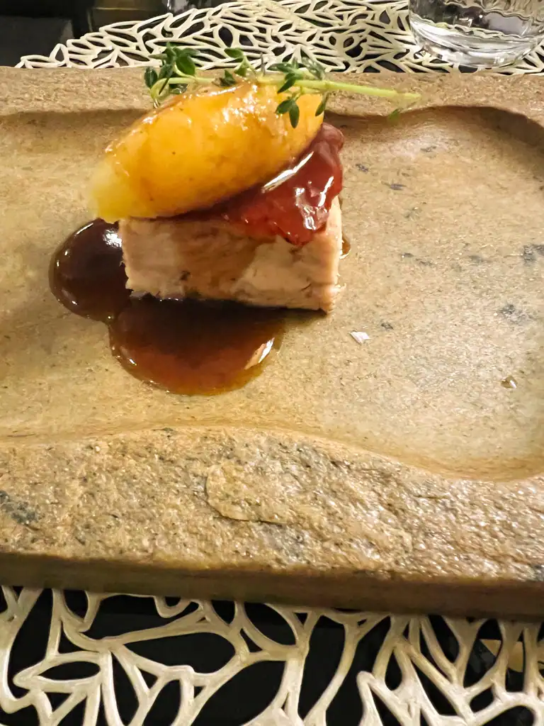 A small pork dish with gravy and a small coop of mashed potatoes. 