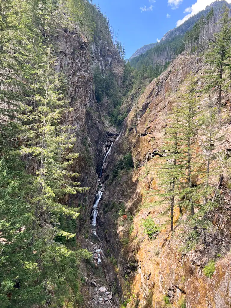 A thin waterfall flowing between two large rocky hills.