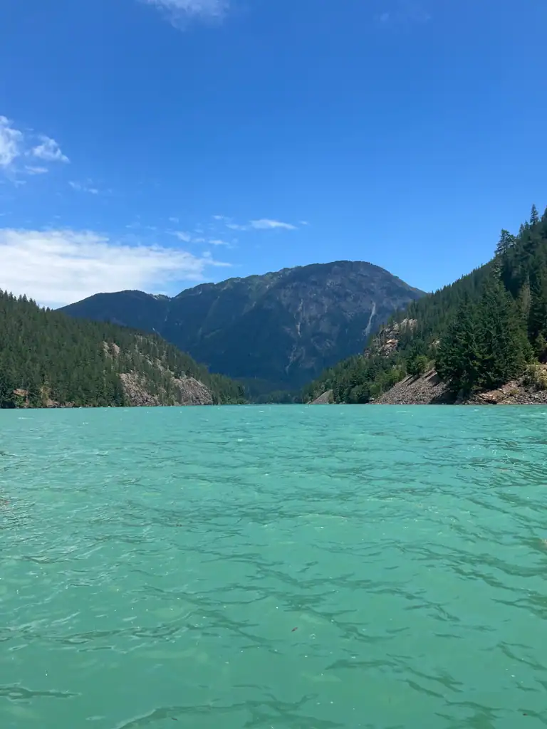 A teal blue lake, at lake level with mountains in the background.