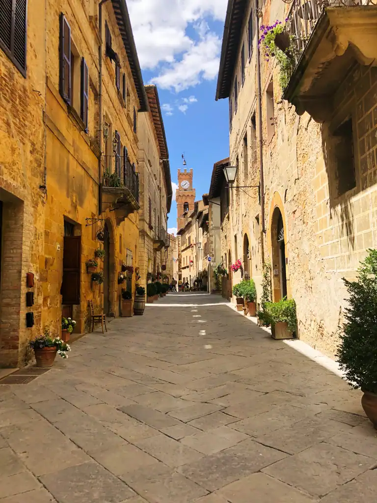 A narrow road in Tuscany with a clock tower in the background. 