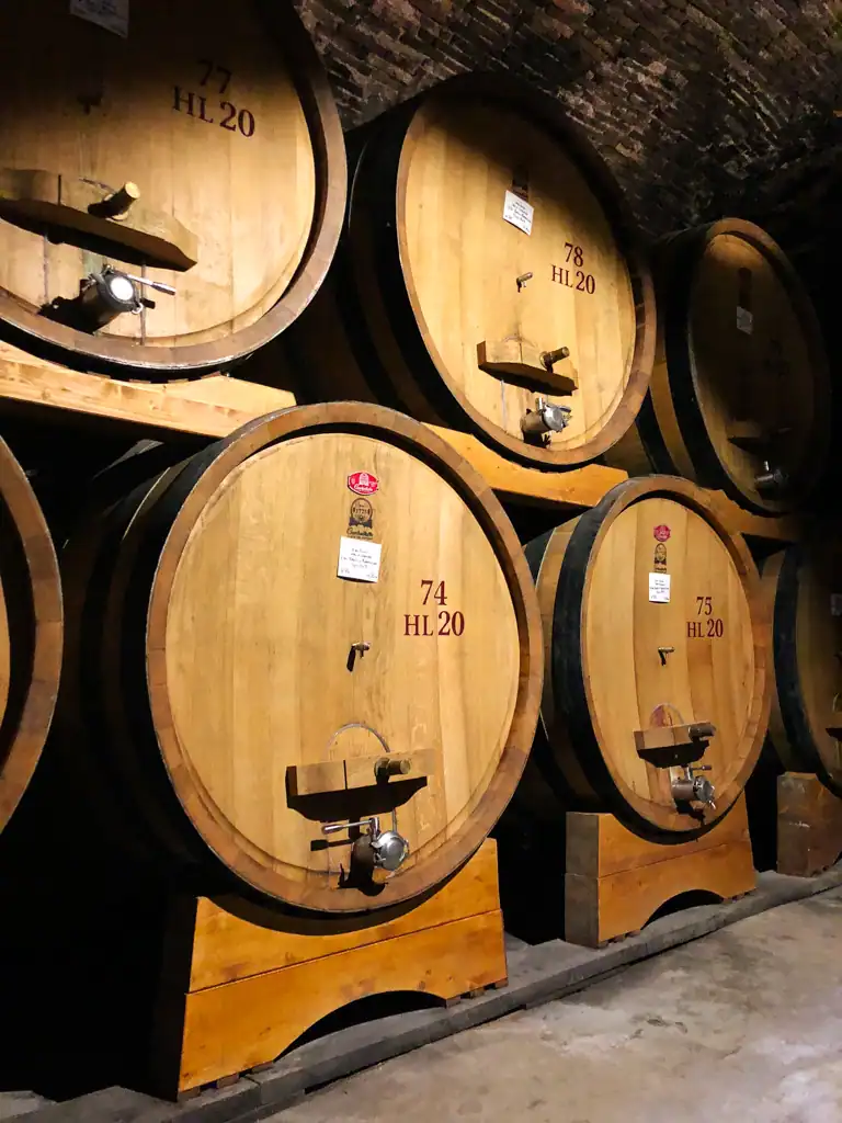 Large, wood wine barrels in a dark wine cave in Tuscany. 