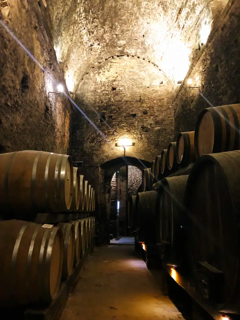 A narrow row of oak wine barrels in a wine cave in Montepulciano. 
