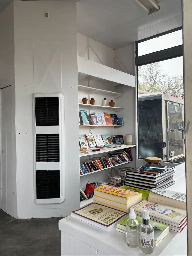 An angle looked a white shelving unit with books, a table with more books. 