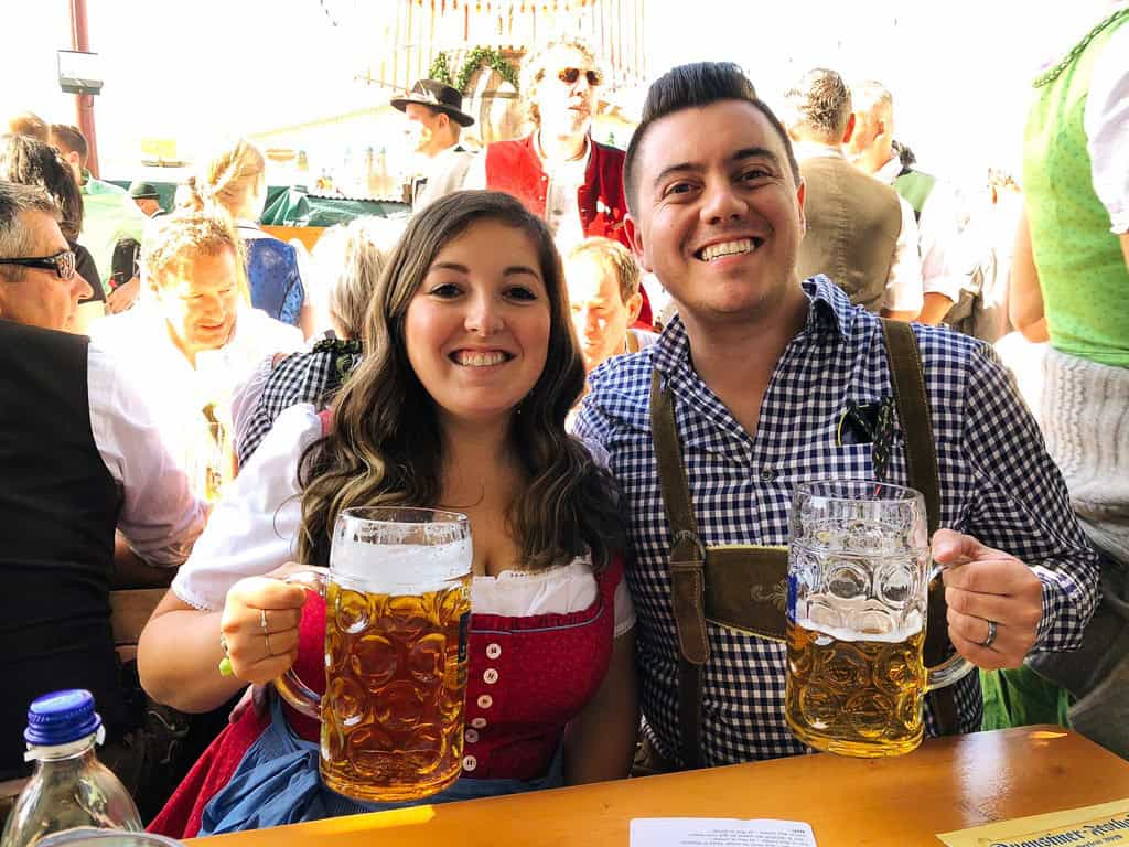 Two people holding steins at Oktoberfest via essential oktoberfest guide. 