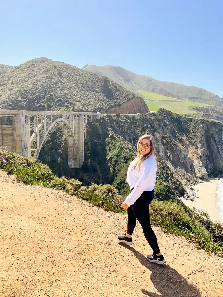 A girl walks toward bixby bridge in this big sur guide. 