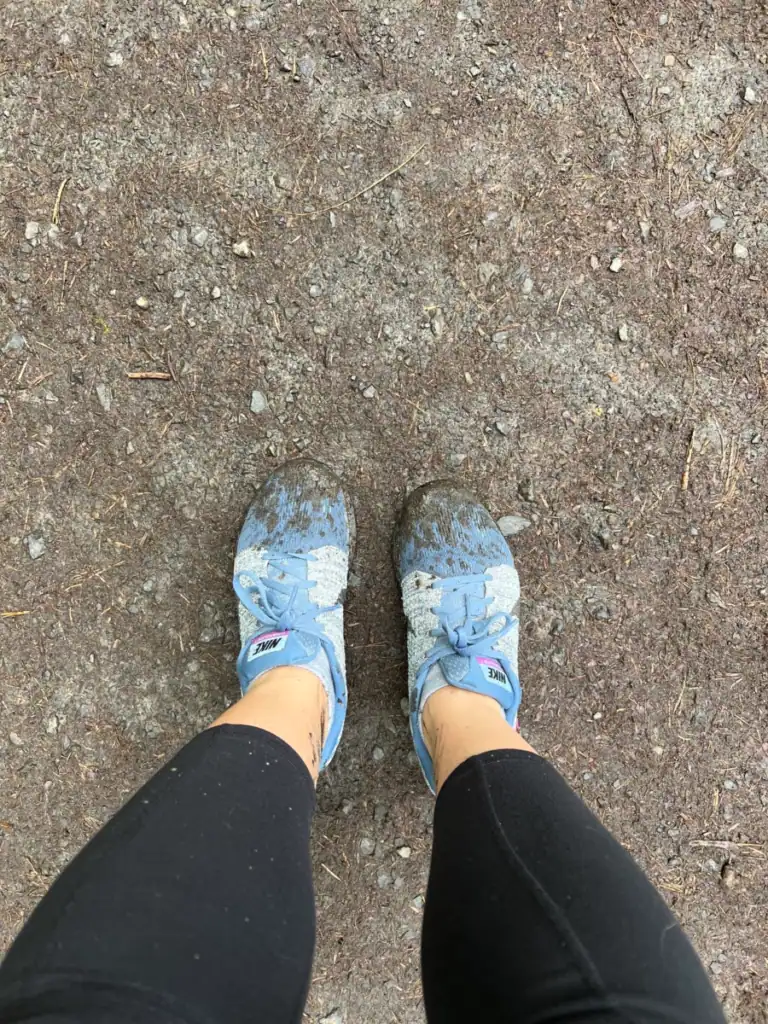 muddy blue nike shoes on a trail in a guide to portland's forest park. 