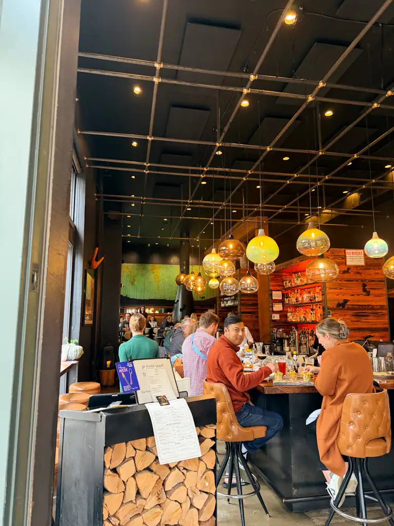 A full bar with creative lighting and chopped wood in a stand. 