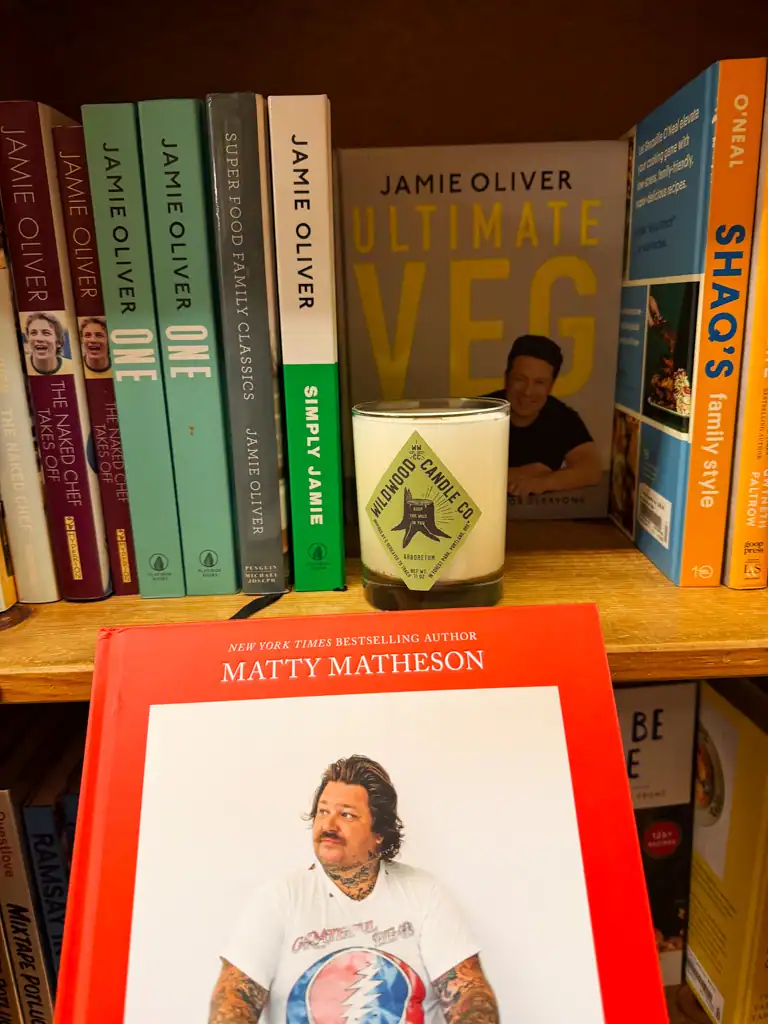 A close up of Matty Matheson's red cook book with a wildwood candle in the background at Powells, one of the best things to do in Portland. 