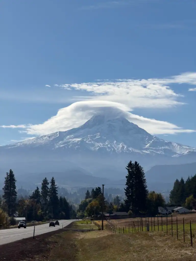 A picture of mt. hood with a cloud hovering over the tip. 