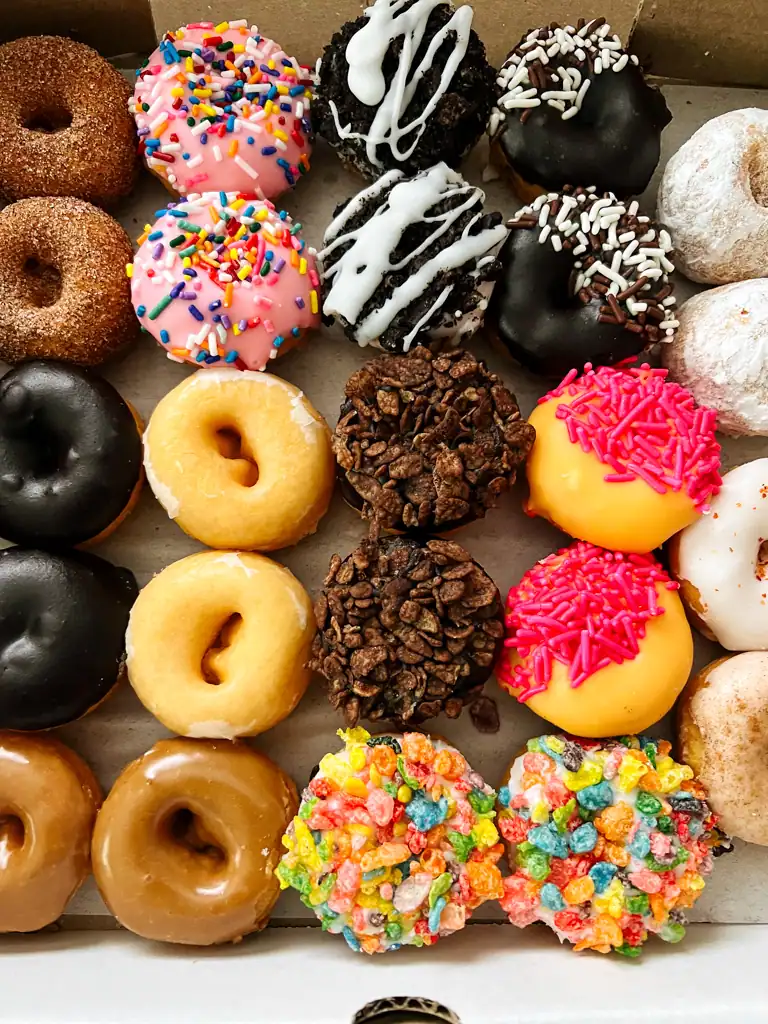 A myriad of mini donuts covered in cereals, sprinkles and frostings. 