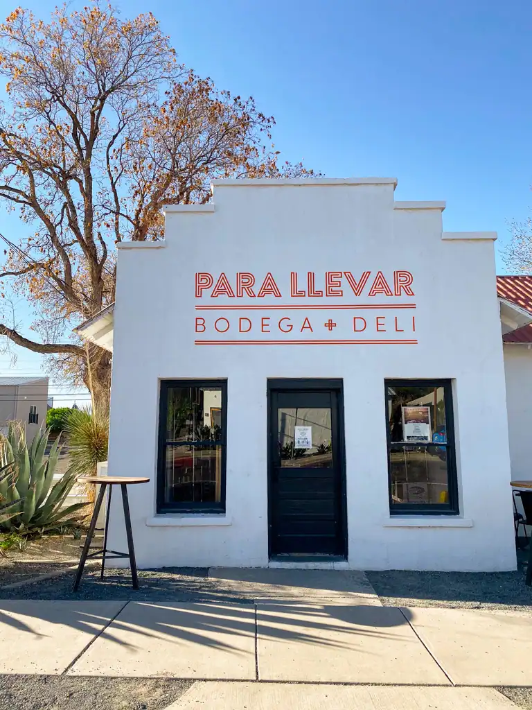 A white bodega made in the aztec style with stucco called Para Llevar Bodega and Deli in Marfa, Texas.