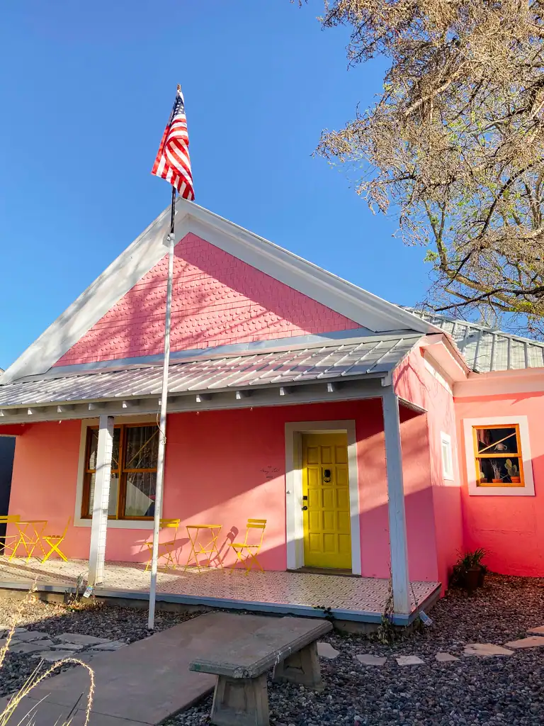 A bright pink house with a yellow door and American flag in Marfa, Texas. 