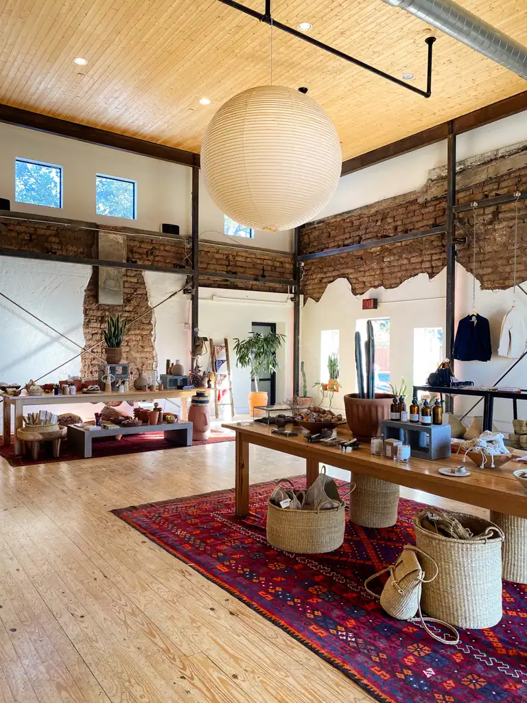 The inside of the sentinal shop in Marfa, Texas. Showcasing a large light fixture and exposed brick walls. 