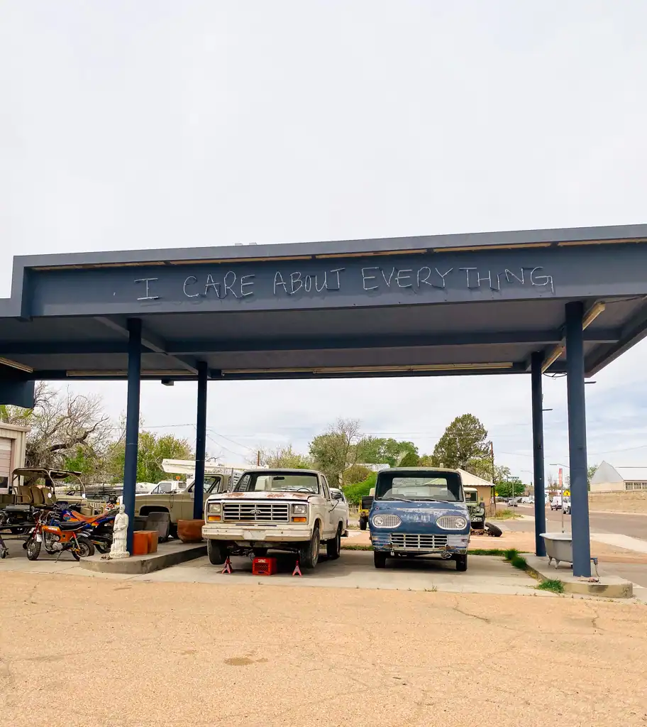 An old car repair shop with lighting on their roof that says "I care about everything". 